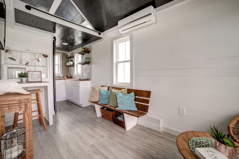 Living area with built-in bench seating, mini-split and sleeping loft above